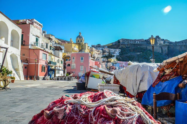 La Corricella in Procida island fishing nets of red color with the panorama of the colorful houses of the marina of bullfighting in the island of raccoon
