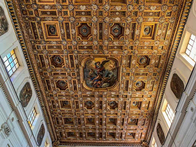 Wooden ceiling of the Abbey St. Michael in Procida island a golden wooden ceiling with a honeycomb shape made of larger and smaller rectangles with a fresco in the center